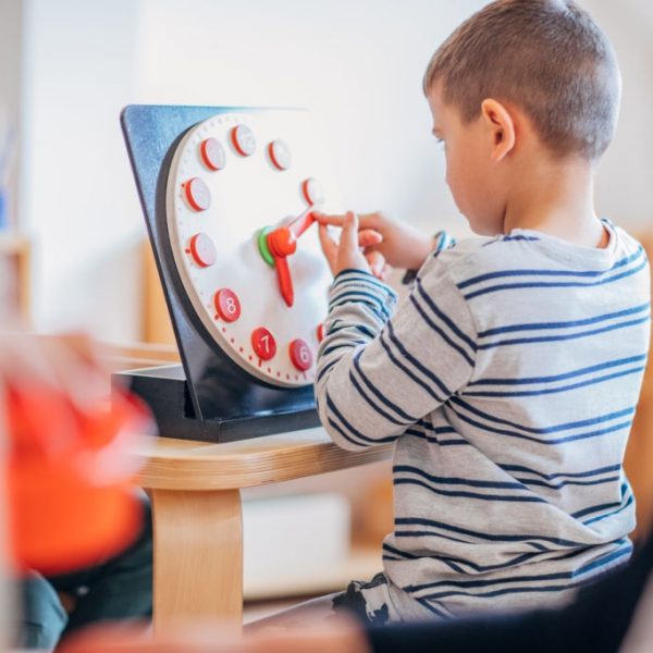 Preschool age boy sitting in classroom and playing with toys.